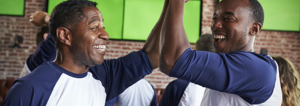 Male Friends Watching Game In Sports Bar Celebrating